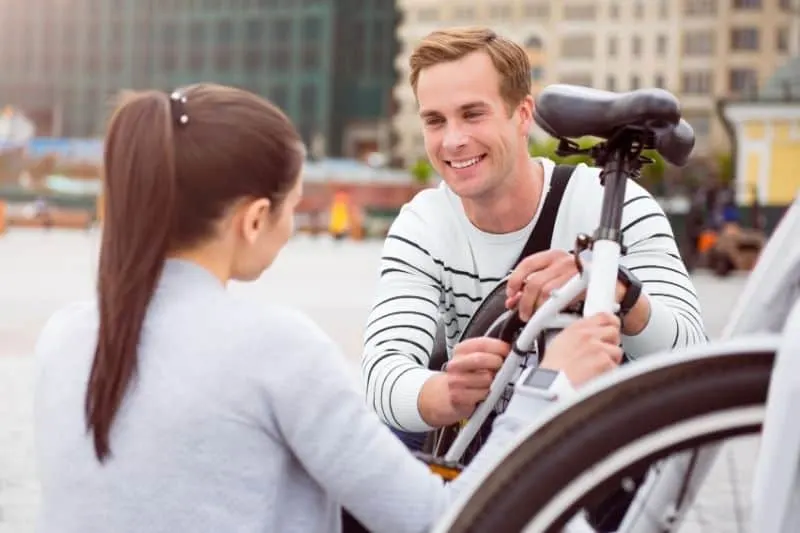 young man looking at a woman while fixing a bike