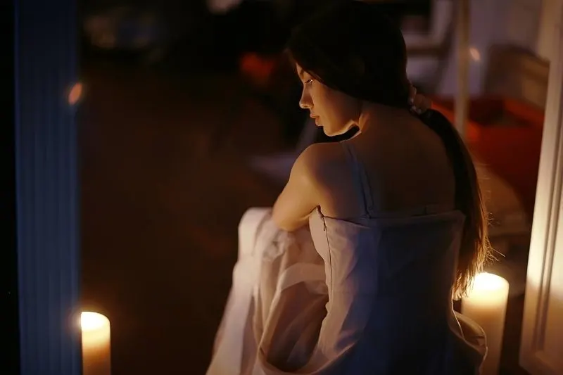 young woman and candles in a romantic set up sitting in a rear view