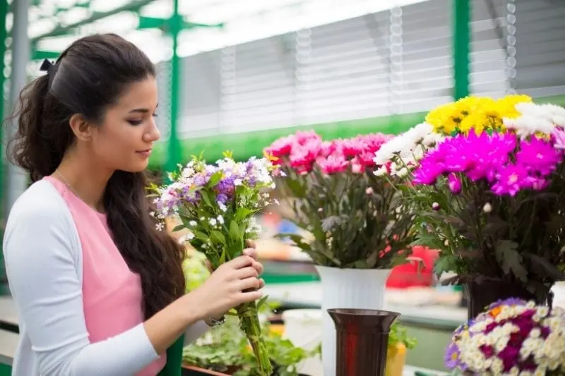 young woman buying flowers at the market holding the bouquet of flowers in sideview image