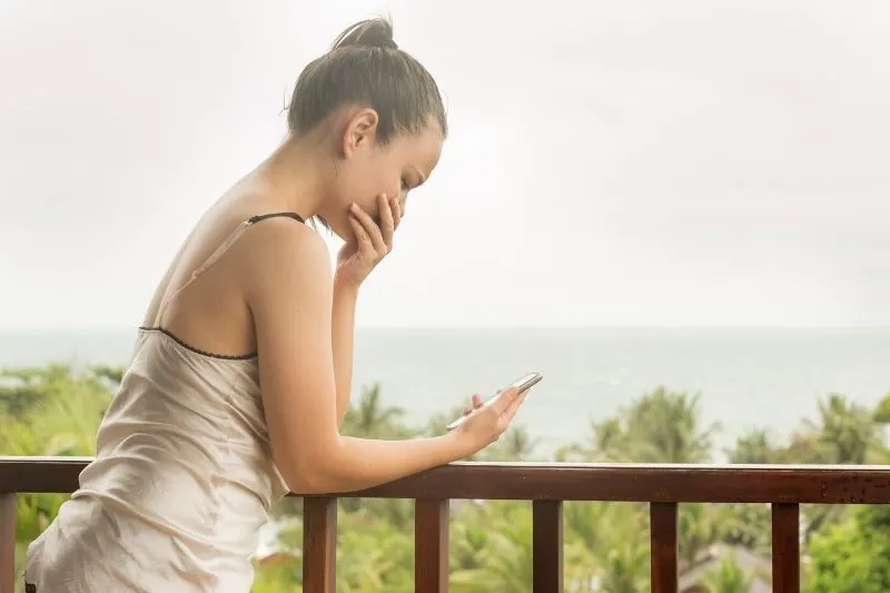 young woman crying looking at the cellphone in the veranda