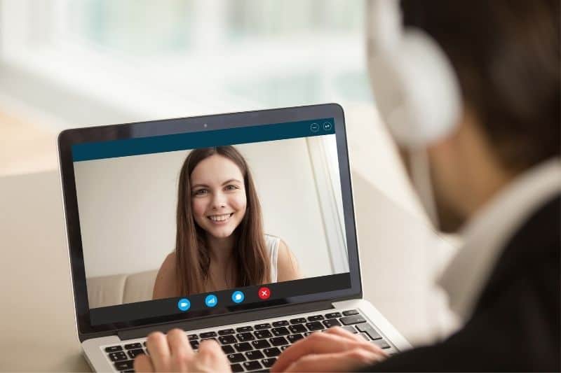 joven en la pantalla del portátil chateando por vídeo con un hombre sentado