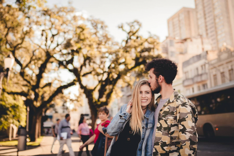 homem a beijar a testa de uma mulher enquanto está na rua