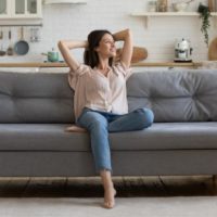 mujer feliz sentada en el sofá dentro de una acogedora sala de estar