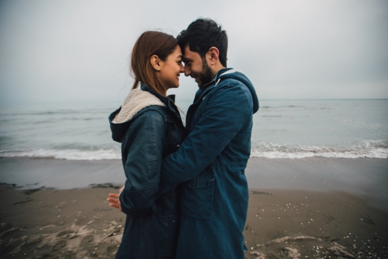 man and woman hugging while standing near sea