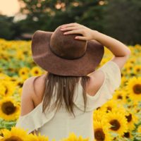 mujer con sombrero de pie en un campo de girasoles