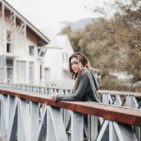 woman in gray cardigan leaning on rail