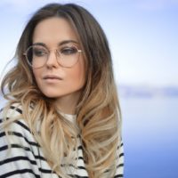 woman with round eyeglasses sitting near water
