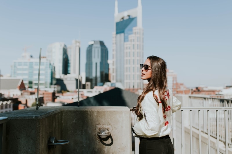 woman with sunglasses standing near hand rails