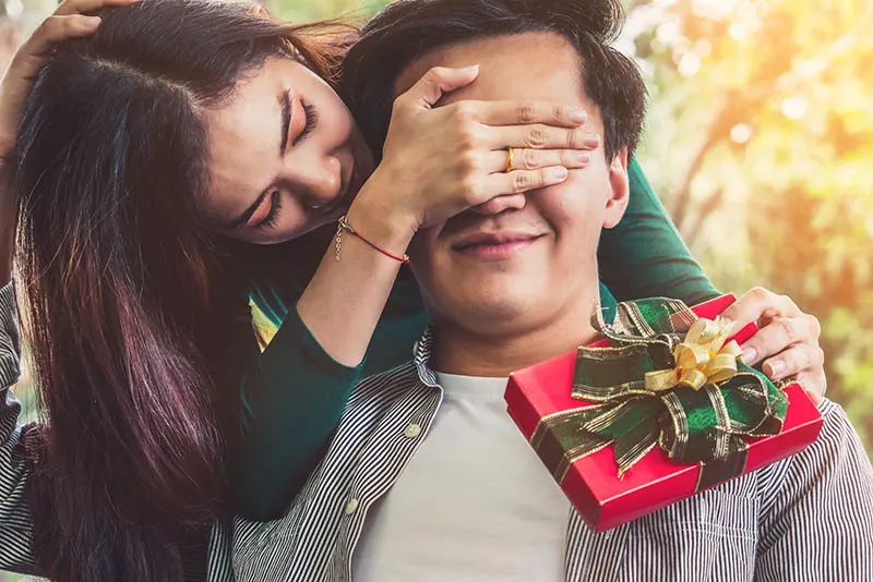 woman surprising boyfriend with christmas present