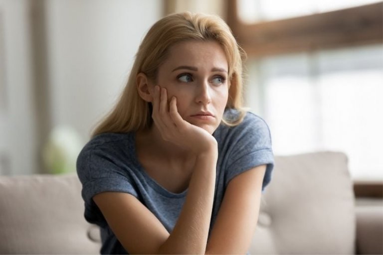 sad woman thinking and sitting in the sofa inside the living room