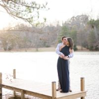 man kissing woman while standing on dock near water