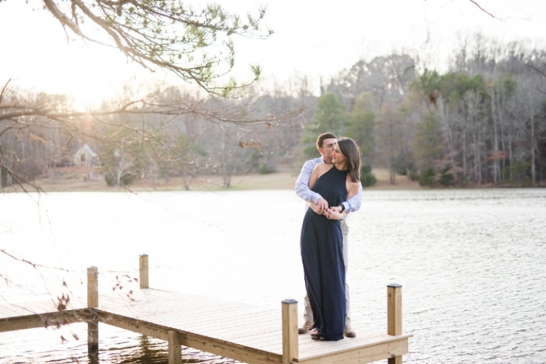 man kissing woman while standing on dock near water