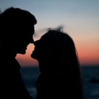 man and woman about to kiss while standing on beach