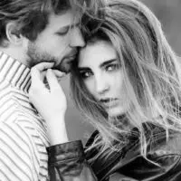 woman with stylish long hair touching the handsome face of the man with a beard in grayscale photography