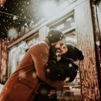 hombre y mujer a punto de besarse en la nieve