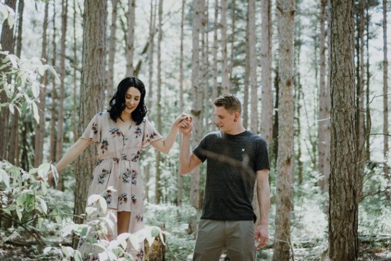 man holding woman's hand while standing in forest