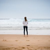 mujer con sudadera blanca mirando al mar