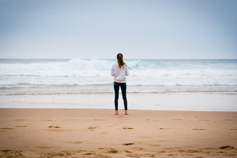 woman in white sweatshirt looking at ocean