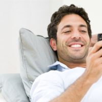 handsome man lying down while texting on his smartphone