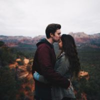 hombre besando la frente de una mujer al aire libre