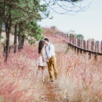 couple kissing while standing near tree