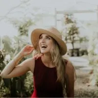 happy woman with hat standing near plants