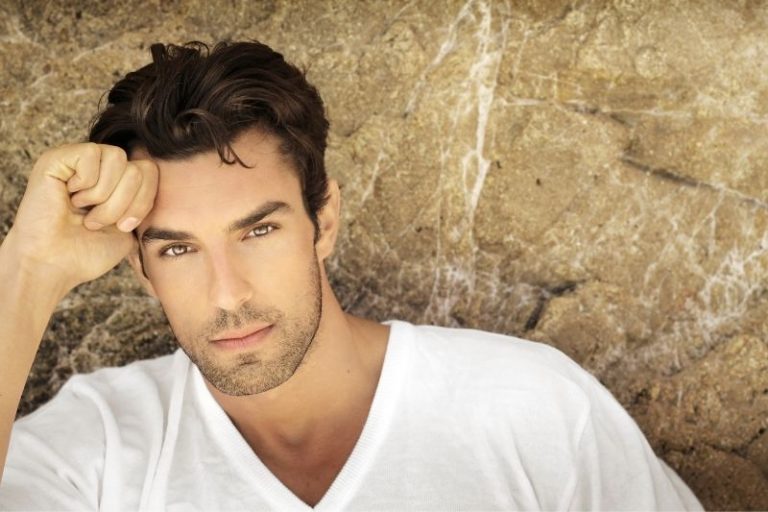 handsome man leaning on the stone wall thinking placing his one hand in his head