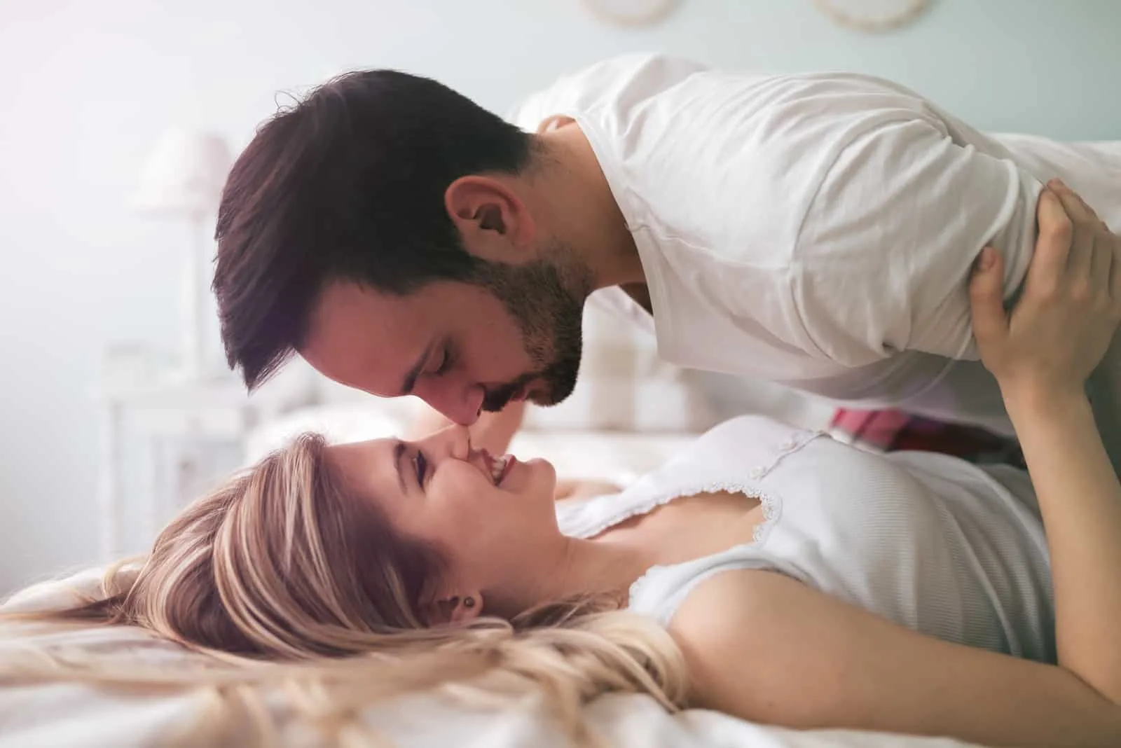 a man and a woman kissing in bed