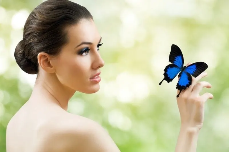 beautiful butterfly woman in sideview with a blue butterfly on her finger