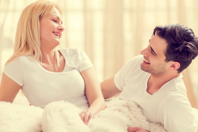 beautiful couple talking cheerfully while in the bed