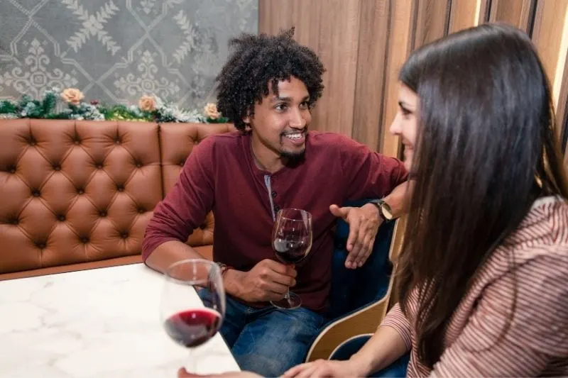 biracial couple in twenties having a date drinking red wine