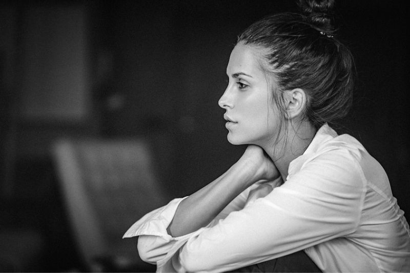 black and white portrait of a pensive woman in white top sideview