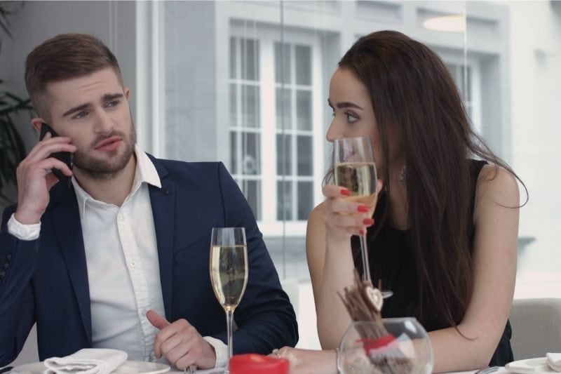 bored woman dining with her boyfriend busy on the phone 