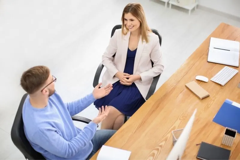 business man and woman talking inside the office sitting on the chair in top angle