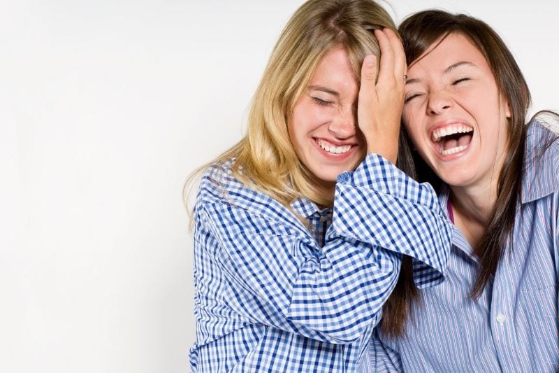 cheerful girl bestfriends laughing wearing pajamas with one girl holding his head