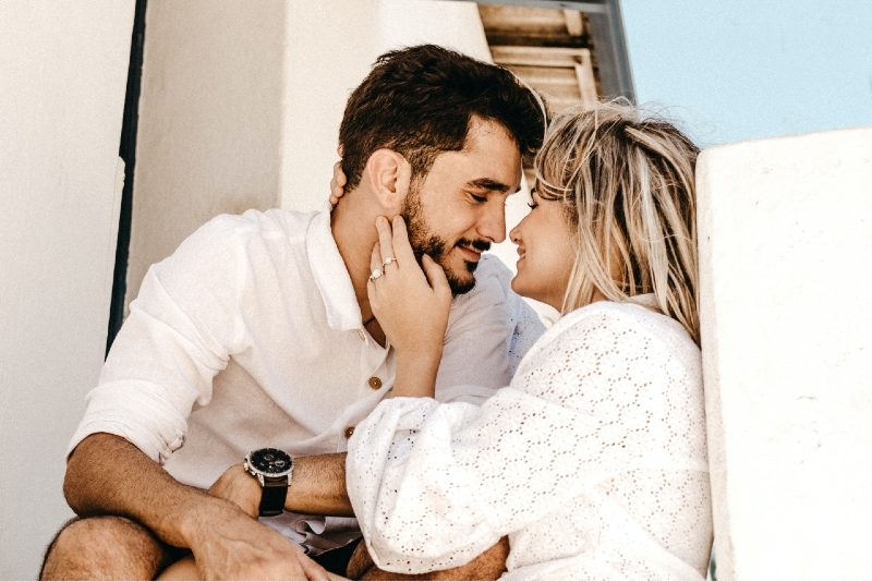 hombre y mujer a punto de besarse sentados al aire libre