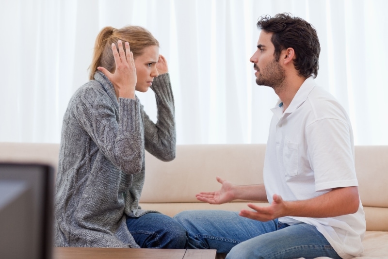 man and woman arguing while sitting on sofa