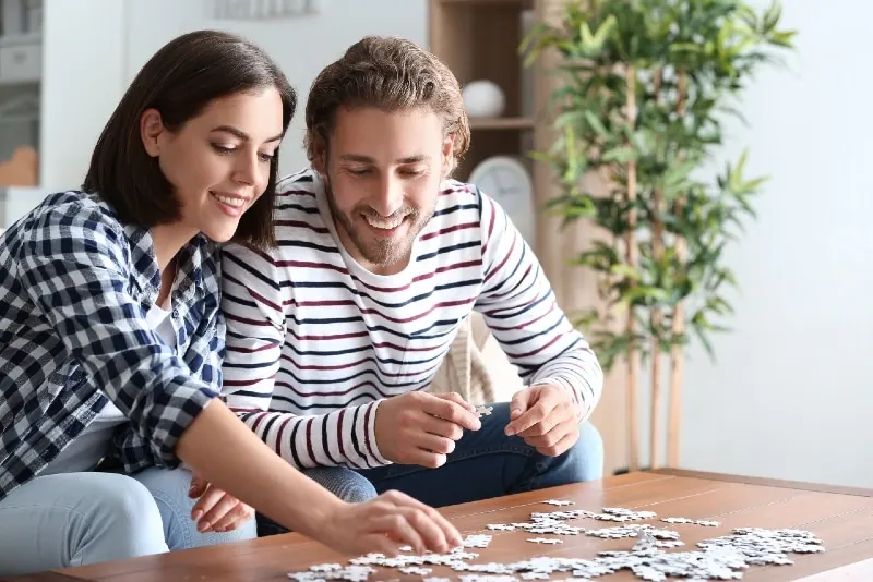 man and woman doing jigsaw puzzle at home
