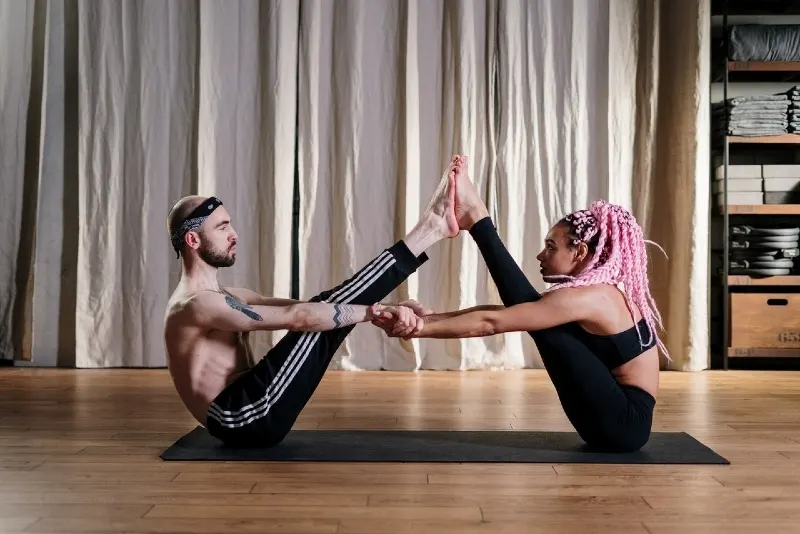 man and woman doing yoga on black mat