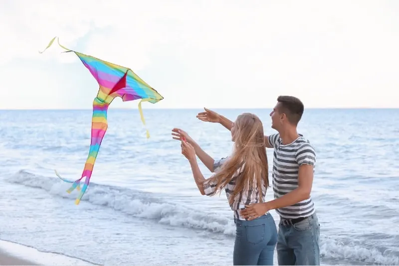 man and woman flying kite near sea