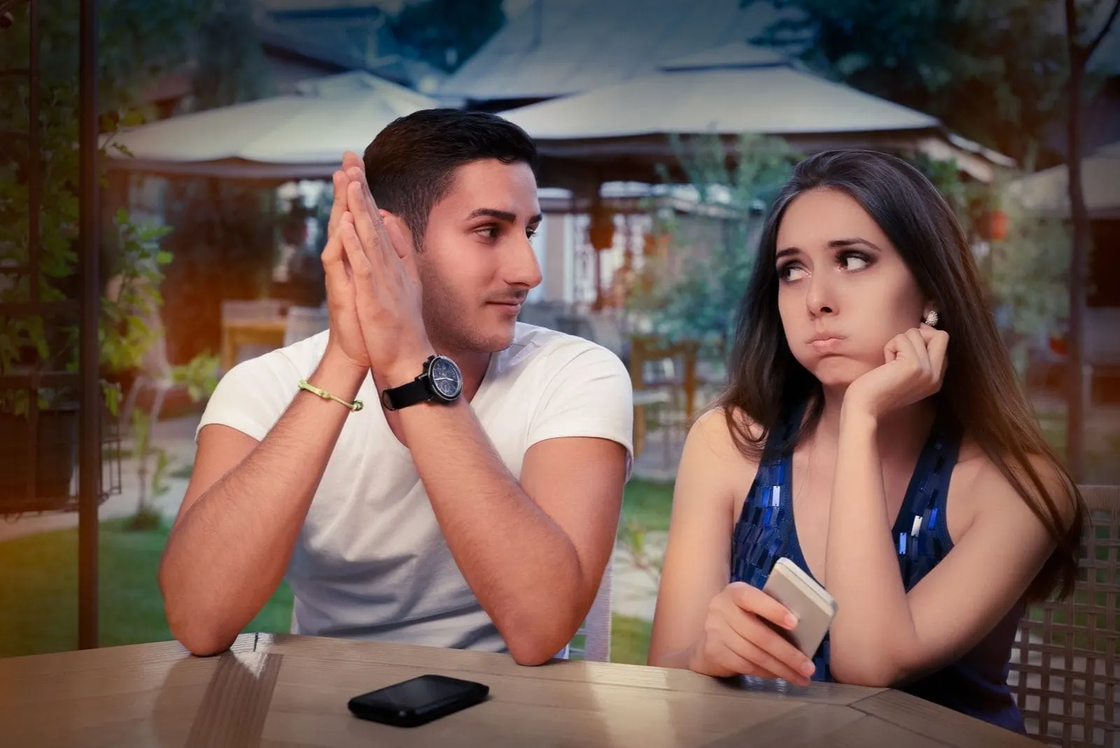 couple having problem with smartphone in an outdoor cafe with woman in disbelief expression