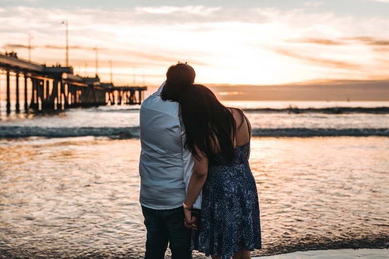 man and woman holding hands while looking at ocean