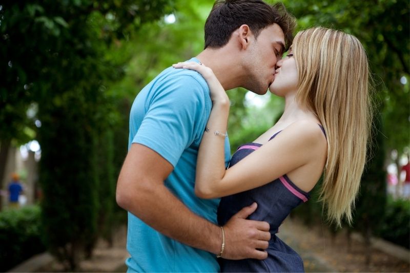 coppia che si bacia nel parco in mezzo alla strada