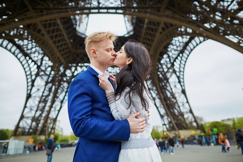 coppia che si bacia romanticamente sotto la torre Eifell in Francia