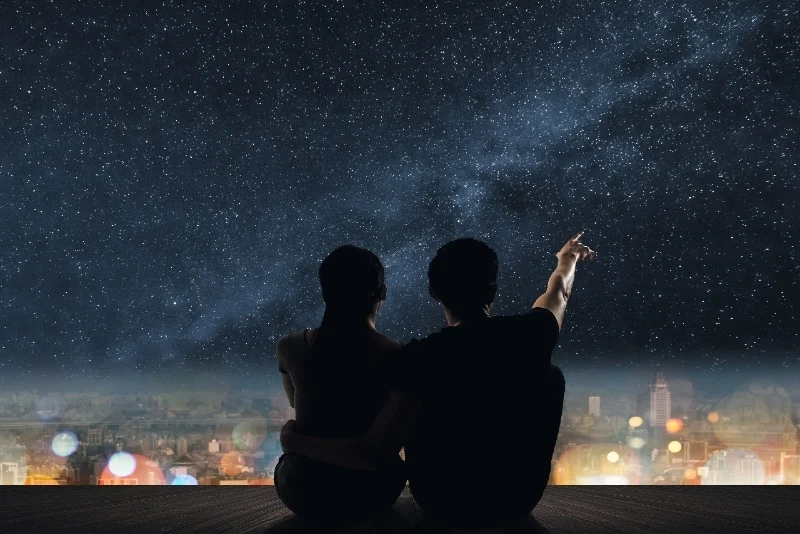 man and woman sitting on rooftop watching stars