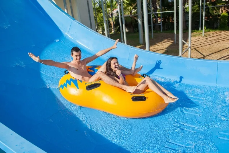 couple sliding down a water slide at public swimming pool