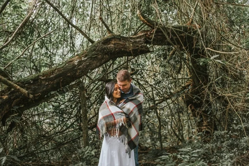 man and woman wrapped with blanket standing near tree