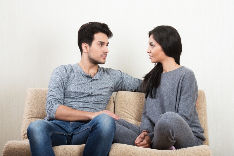 man and woman talking while sitting on sofa