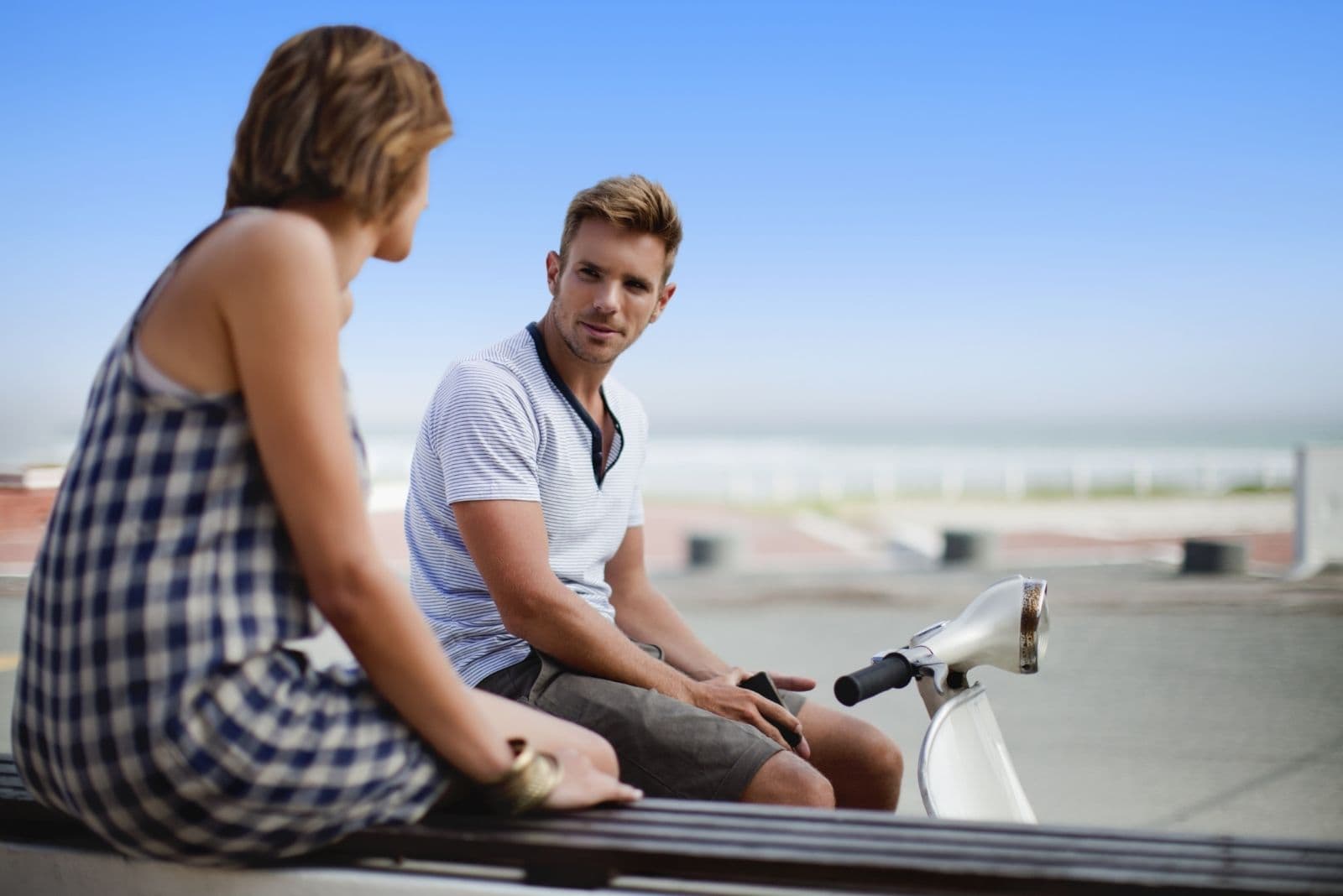 couple talking outdoors sitting with a motorbike in the street