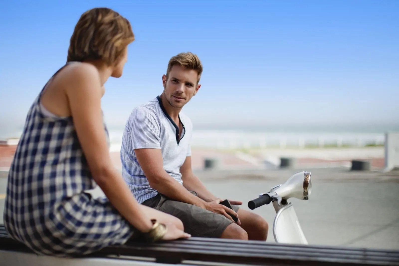 couple talking outdoors sitting with a motorbike in the street